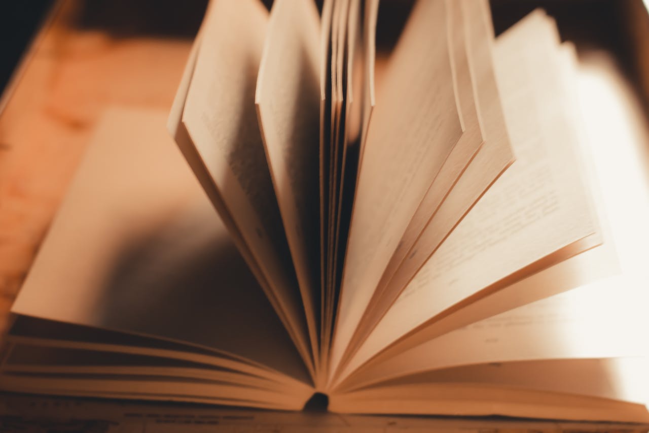 Close-up of an open book with pages turning in warm, soft light.