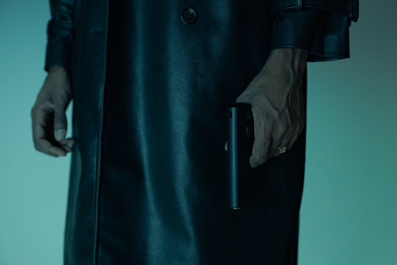 Close-up of an unrecognizable person holding a pistol, creating a mysterious and suspenseful mood.