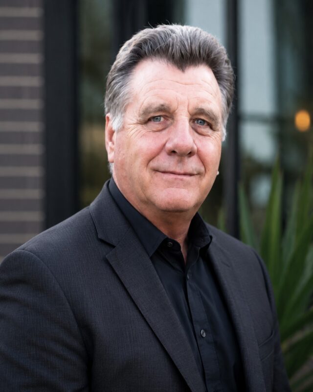 Author Roger Bray professional headshot for psychological thriller books, outdoor portrait with modern blurred background showing confidence and author branding.